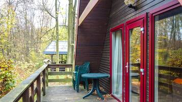 Une terrasse en bois avec une porte vitrée et une petite table.