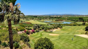 A golf course with a clear view of the landscape, including a palm tree and distant hills. - S o Rafael Beach House (Albufeira)