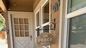 A porch with two blue Adirondack chairs and a welcome mat. - The Grand Adventure (Grand Junction)