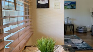 A kitchen with wooden blinds, a coffee-themed wall art, and a green plant on a marble countertop. - The Grand Adventure (Grand Junction)