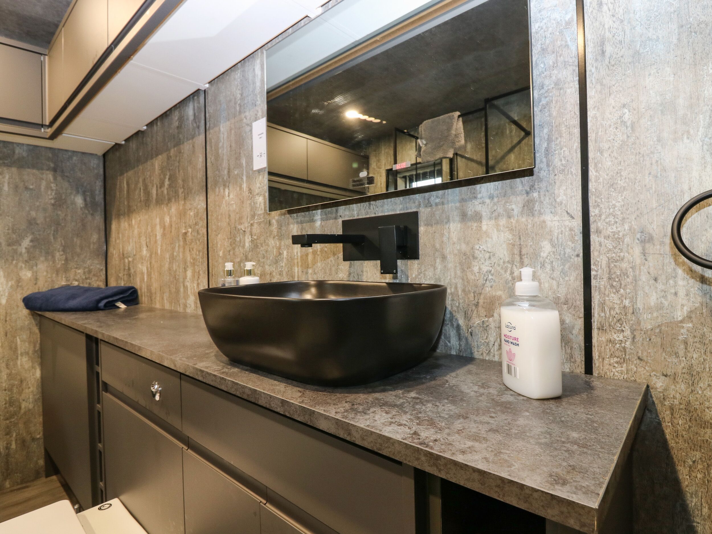 A modern bathroom with a large vessel sink, a mirror, and a towel on the counter.