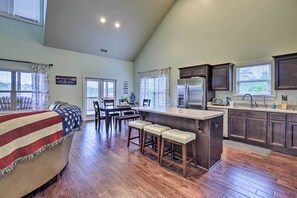 Una cocina amplia con una isla grande, taburetes de madera y un comedor con mesa y sillas.