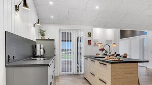 Cozinha moderna com ilha central, eletrodomésticos embutidos e iluminação pendente.
