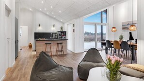 Cozinha moderna com bancada preta, banquetas de madeira e área de jantar com mesa e cadeiras.