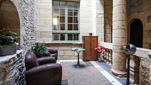 Un patio con paredes de piedra, un espacio de estar, una mesa y un cuenco decorativo.