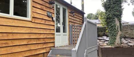 A wooden house with a front door, a small porch, and a wooden fence.