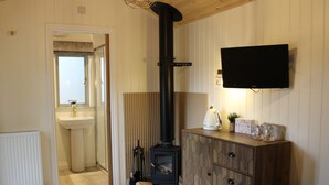 Ein gemütliches Wohnzimmer mit Kamin, einem an der Wand befestigten Fernseher und einer Holzkassette.