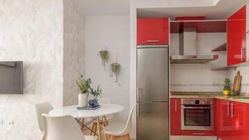 Una cocina moderna con armarios rojos, un refrigerador de acero inoxidable y un horno empotrado.