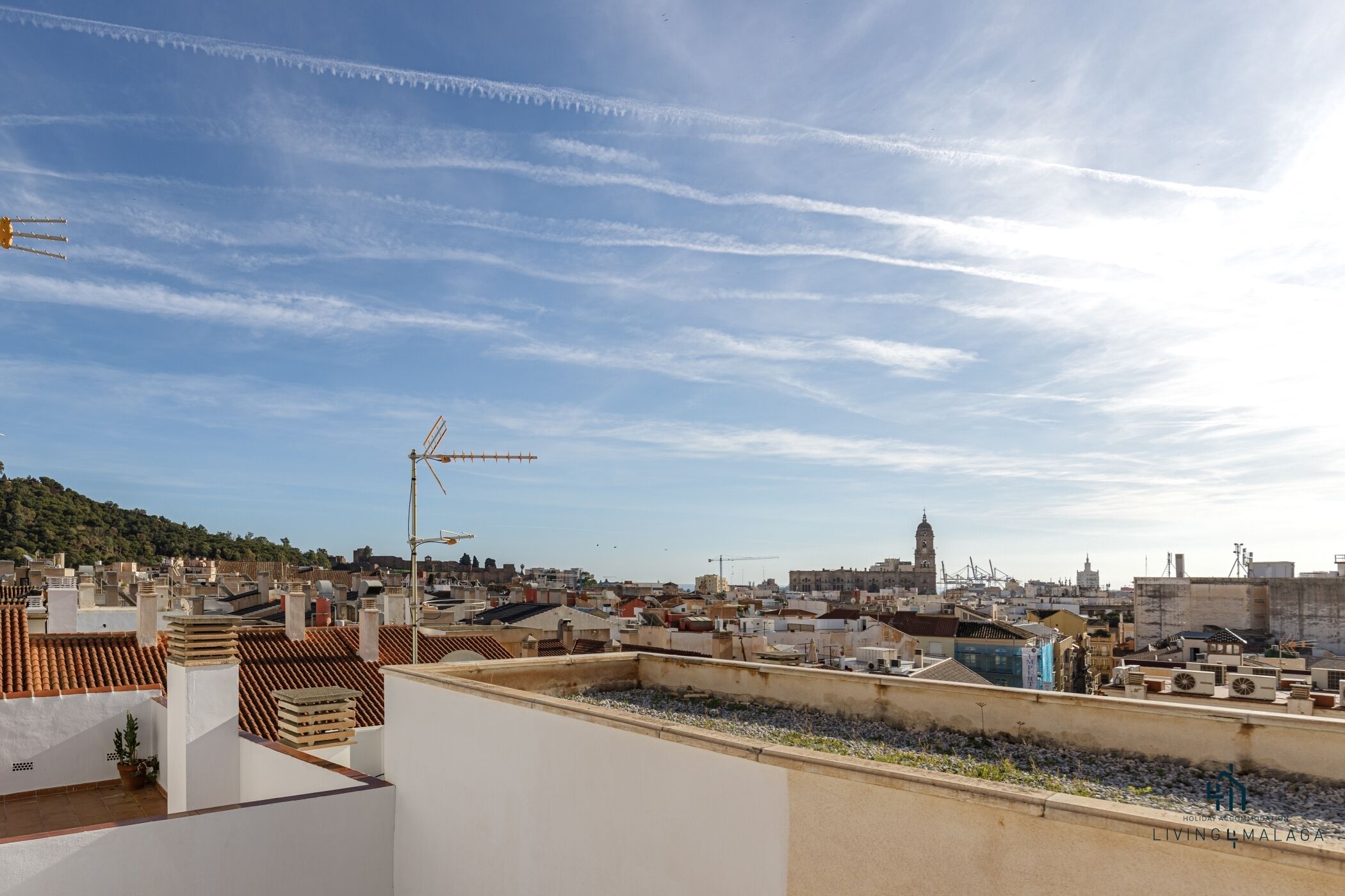 A rooftop terrace with a clear view of a cityscape, including buildings and a distant tower.