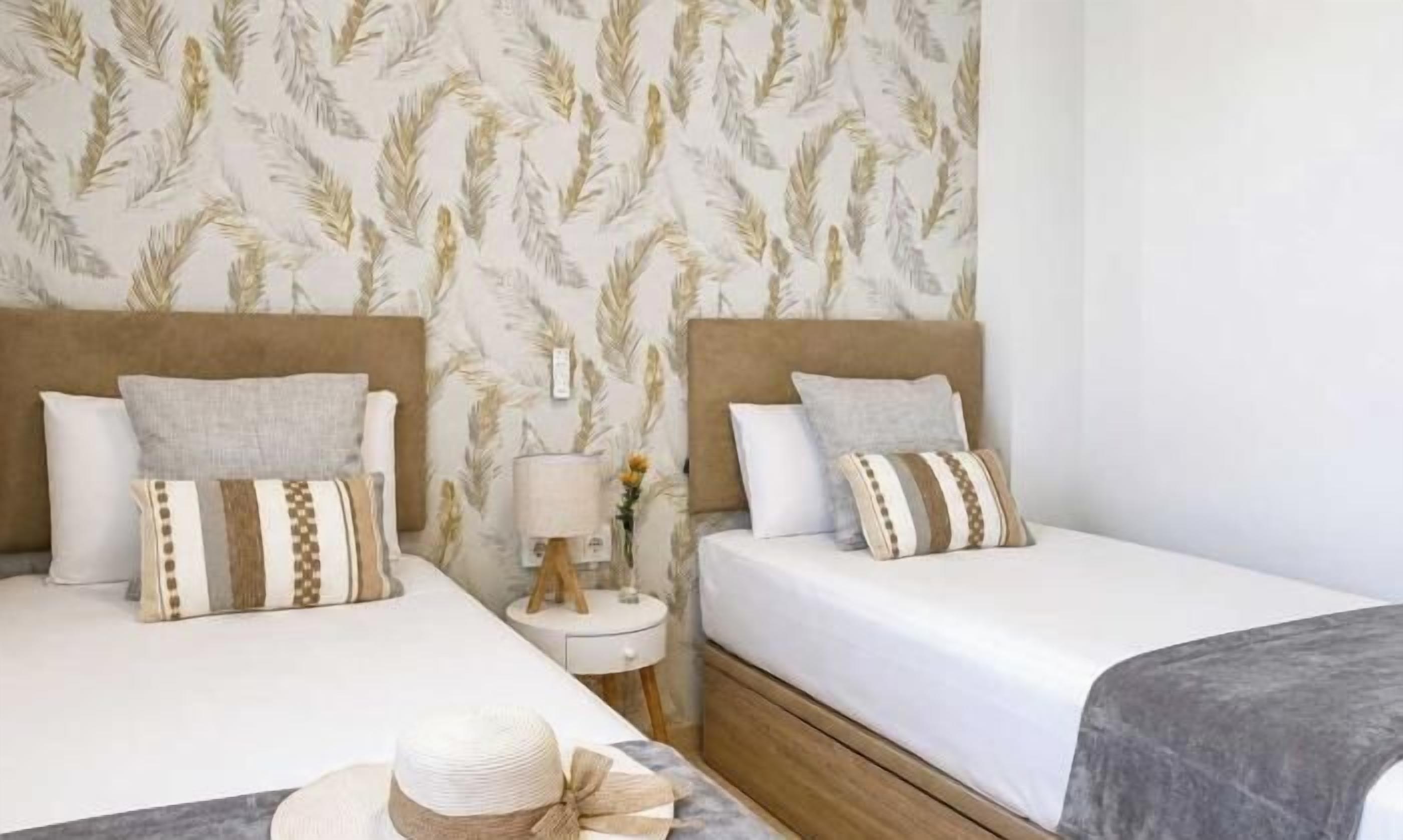 A hotel room with two beds, a nightstand with a lamp, and a decorative wall.