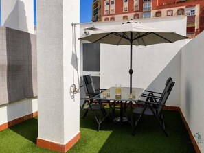 A patio with a table and chairs, an umbrella, and artificial grass. - City Views Terrace Living4malaga (Málaga)