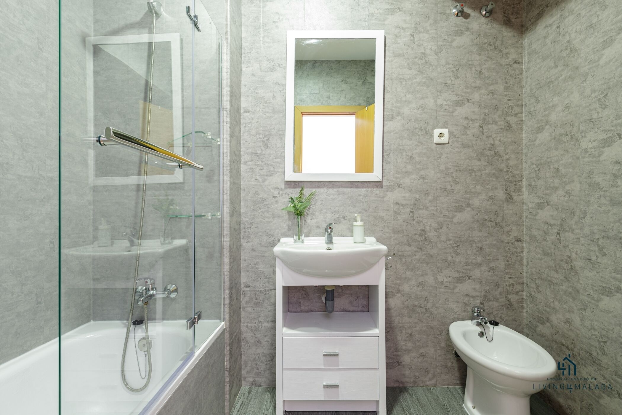Un baño moderno con ducha de vidrio, un lavamanos pedestal blanco y un inodoro.