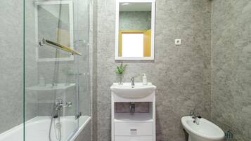 Un baño moderno con ducha de vidrio, un lavamanos pedestal blanco y un inodoro.