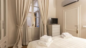 A hotel room with a bed, a TV, a wardrobe, and a door. - Rucellai Prestige in Florence by Mmega (Firenze)