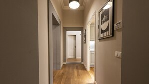A hallway with wooden flooring, a light fixture, and framed artwork on the walls. - Rucellai Prestige in Florence by Mmega (Firenze)