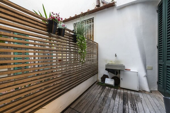 A wooden slatted fence, a small sink, and potted plants in a narrow outdoor space. - Rucellai Prestige in Florence by Mmega (Firenze)