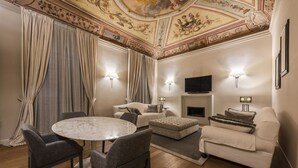 A living room with a round table, grey chairs, a sofa, and a television. - Rucellai Prestige in Florence by Mmega (Firenze)