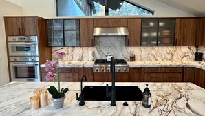 A modern kitchen with marble countertops, stainless steel appliances, and wooden cabinetry. - Luxe Vail! 5 minutes to town. Dual Primary - Hot Tub - Free Ski Bus! Sleeps 10 (Vail)