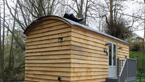 Une cabane en bois avec un toit incurvé, une porte et un petit porche.