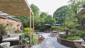 An outdoor patio area with seating, tables, and umbrellas. - Blue Piano (Birmingham)
