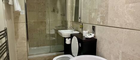 A modern bathroom with a glass-enclosed shower, a white toilet, and a freestanding bathtub.