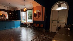 A bar area with a counter, chairs, and a patterned rug. - Blue Piano (Birmingham)