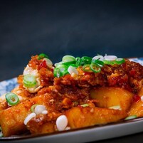 A plate of nachos topped with cheese, ground meat, and green onions.