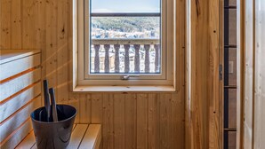 A wooden cabin with a window overlooking a snowy landscape.