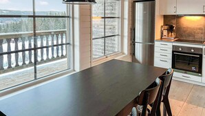 A modern kitchen with a large island, stainless steel appliances, and a view of a snowy landscape through large windows.