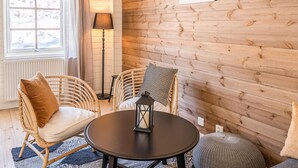 A cozy room with a round table, wicker chairs, a floor lamp, and a view of a snowy landscape through a window.