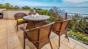 A round outdoor table with wicker chairs, a small table lamp, and a view of the sea. - Beautiful apartment in Moscenicka Draga with WiFi (Moscenicka Draga)