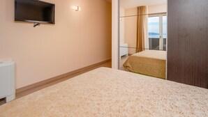 A hotel room with a bed, a television mounted on the wall, and a window with curtains. - Beautiful apartment in Moscenicka Draga with WiFi (Moscenicka Draga)