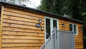 Une cabane en bois avec une véranda, une porte et deux fenêtres.