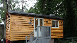 Une cabane en bois avec un petit porche et une seule chaise.