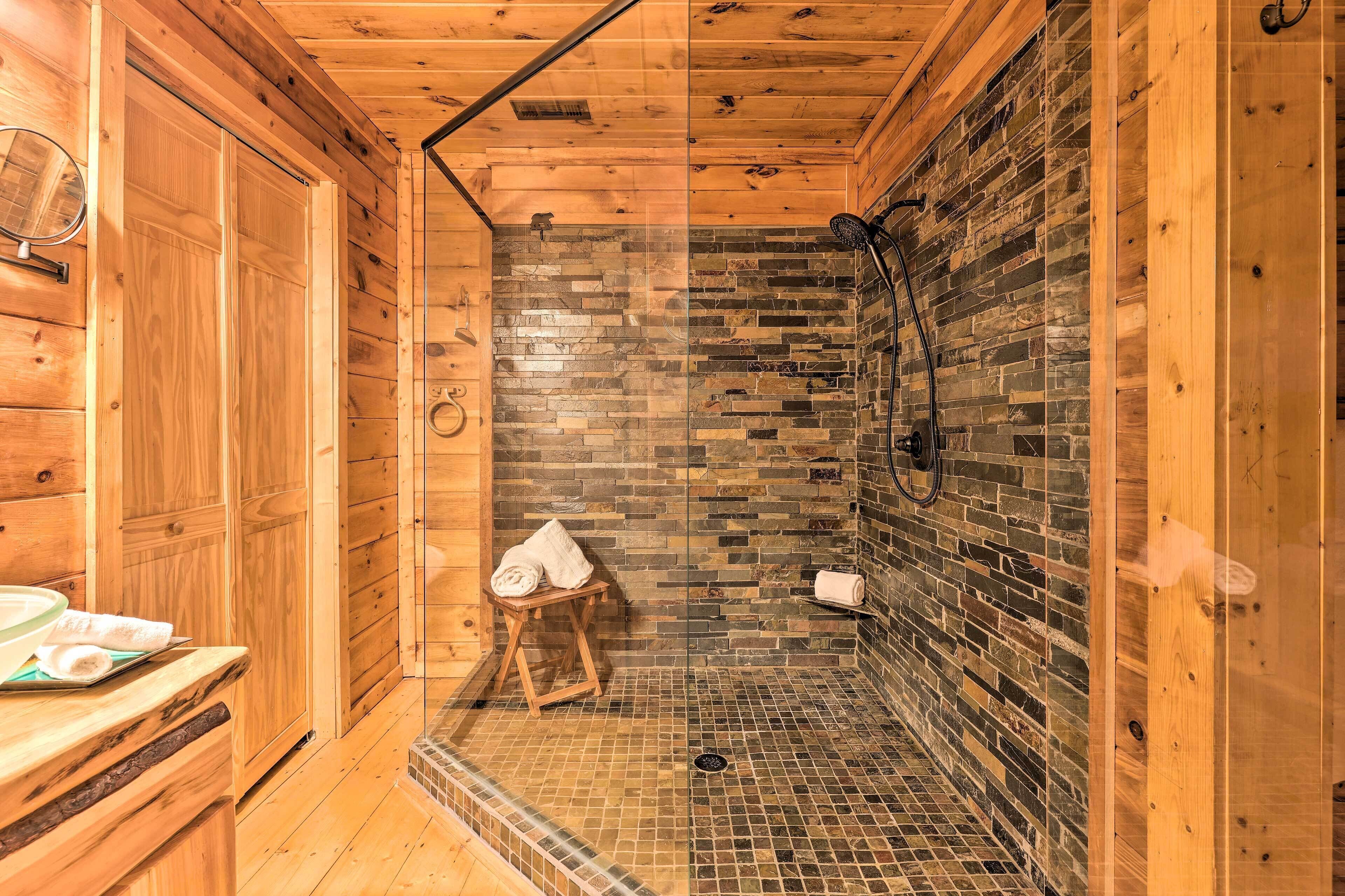 Une salle de bain rustique, aménagée dans une cabane en bois, avec une douche, un banc en bois et un porte-serviettes.