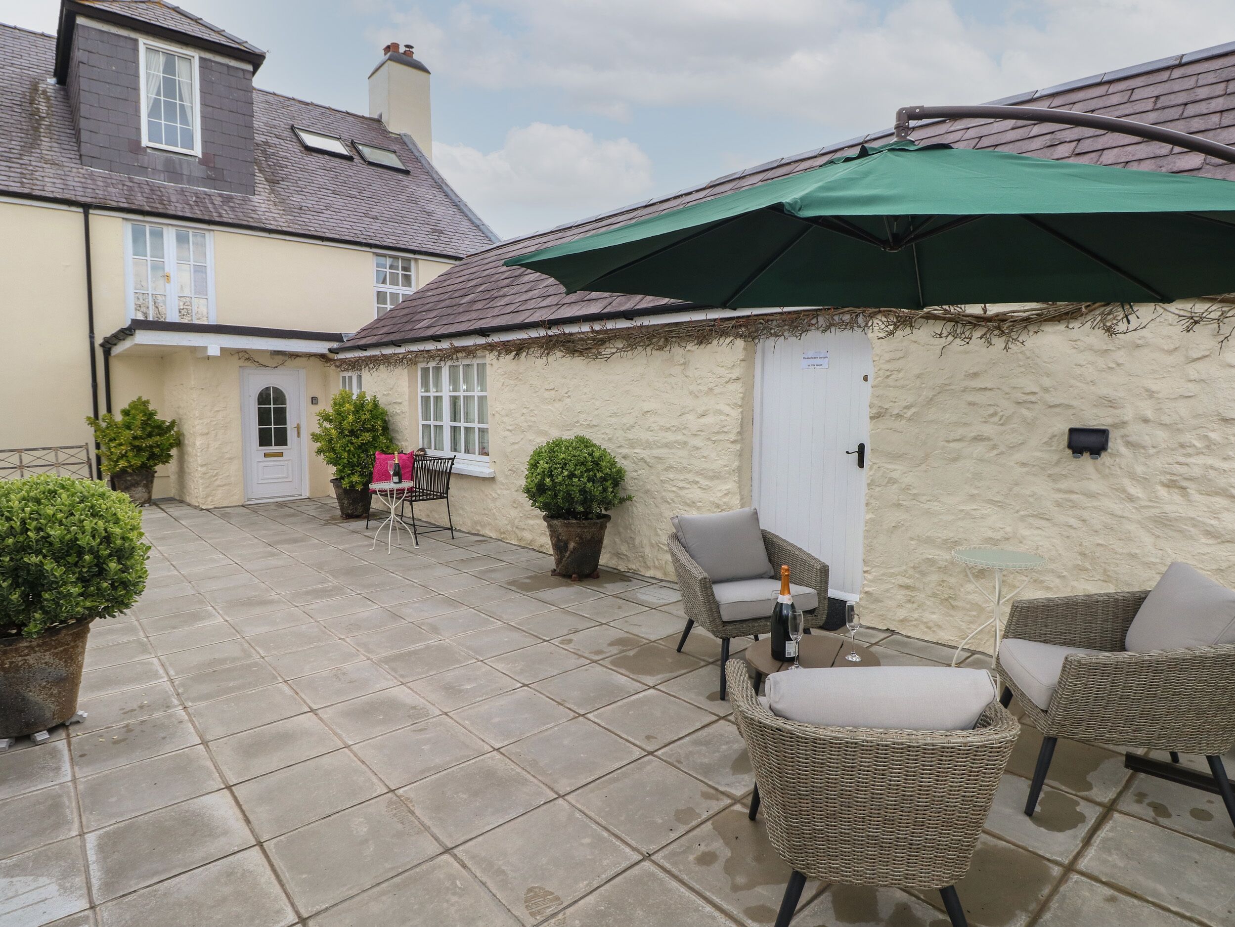 A patio with outdoor furniture, a green umbrella, and potted plants.