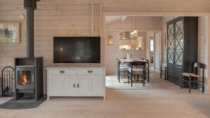 A cozy living room with a fireplace, a TV, and a dining area. - Pet friendly home in Hornbæk with WiFi (Hornbæk)