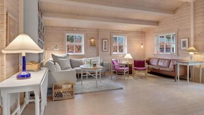 A cozy cabin interior with a wooden interior, a white sofa, a leather couch, a dining table, and a wicker basket labeled "Rum". - Pet friendly home in Hornbæk with WiFi (Hornbæk)