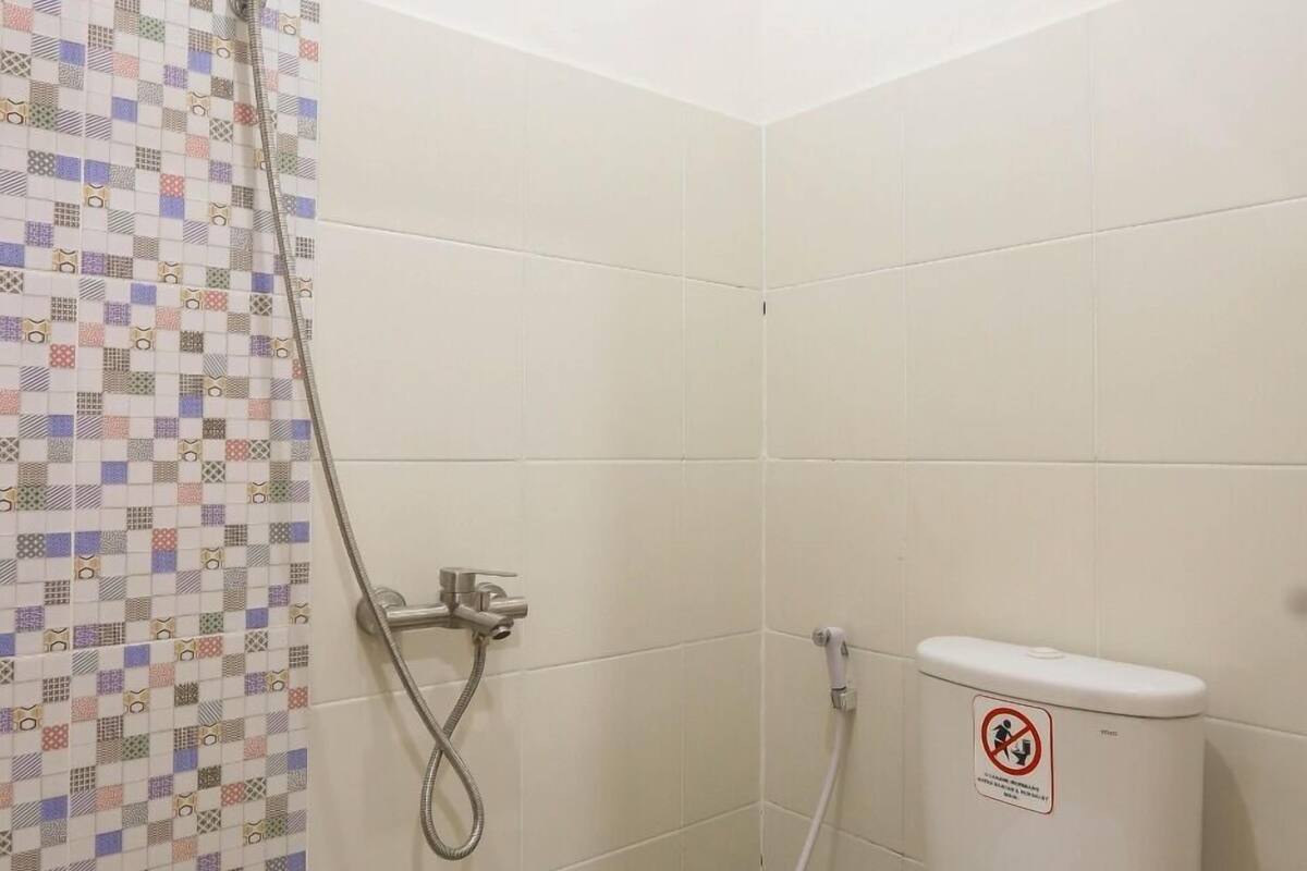 Une salle de bain avec douche, toilettes et carrelage au sol.