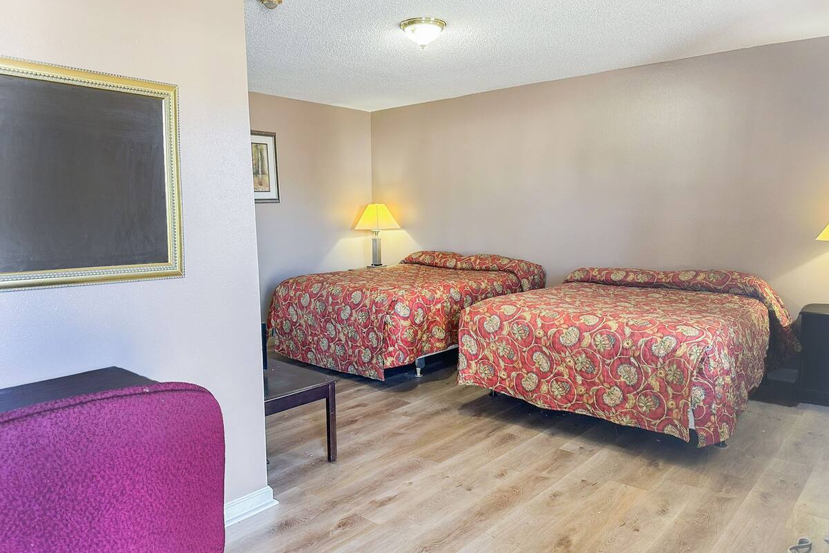 A hotel room with two beds, a desk, and a chair.