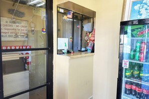 Una máquina expendedora con diversas bebidas, una ventana con vista a la calle y un cartel que indica se requiere identificación para estacionar.