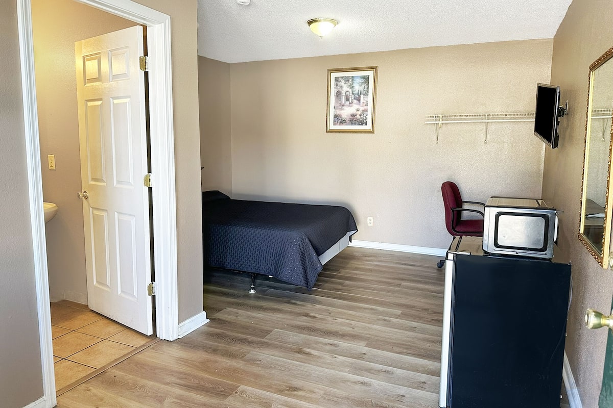 A bedroom with a bed, a television, and a dresser.