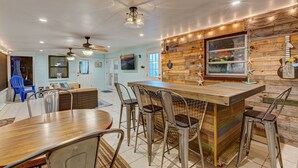A modern kitchen with a wooden island, bar stools, and a ceiling fan. - Brian and Sarahs Hidden Gem (Merritt Island)