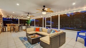 A covered outdoor seating area with a sofa, chairs, and a dining table. - Brian and Sarahs Hidden Gem (Merritt Island)