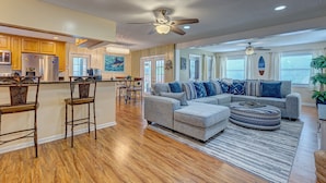 A spacious living area with a gray sectional sofa, a round ottoman, and a wooden dining table with chairs. - Brian and Sarahs Hidden Gem (Merritt Island)