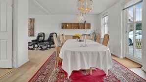 A dining area with a round table, chairs, a chandelier, and a view through large windows. - 3 bedroom beautiful home in Bryrup (Bryrup)