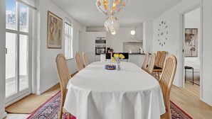 A dining area with a round table, chairs, a chandelier, and a view of the kitchen in the background. - 3 bedroom beautiful home in Bryrup (Bryrup)