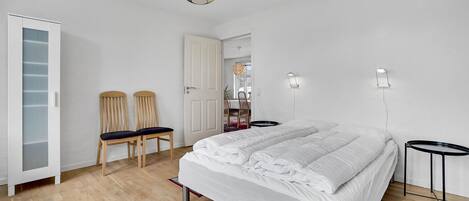 A bedroom with a bed, two chairs, a wardrobe, and two bedside tables.