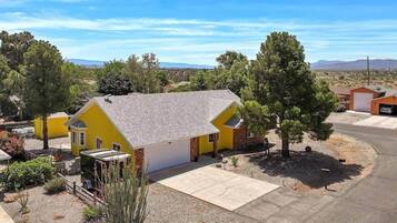 A yellow house with a garage, surrounded by trees and a clear sky.