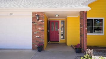 A yellow house with a red door, a garage, and a brick pillar.